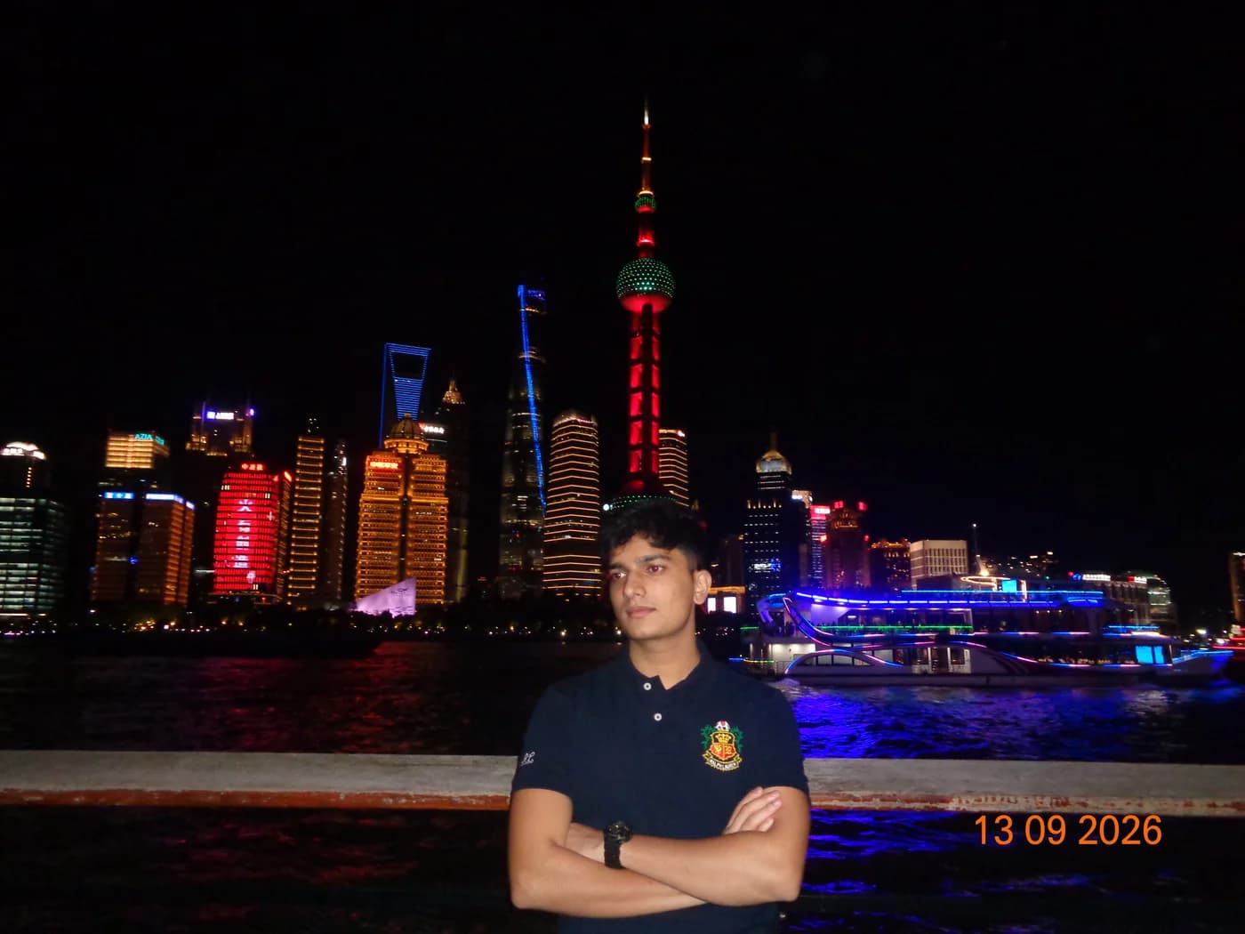 Om by the Huangpu River with Shanghai's illuminated skyline behind him